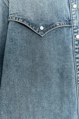 Camisa de denim celeste, de corte recto, con cuello solapa, manga larga, dos bolsillos frontales con solapa y cierre frontal con botones.