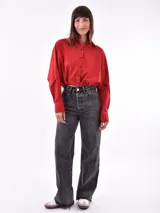 Camisa corta a la cintura, a rayas verticales azules y blancas, con cuello clásico y cierre frontal con botones negros.