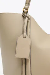 Bolso de hombro tipo shopper color beige, con doble asa y cierre imantado. Incluye una cartera interior con cierre de cremallera.