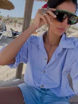 Camisa celeste a rayas verticales con bordados de un sol y un caballo en la espalda.