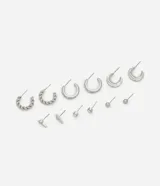 Set de aros plateados con diferentes diseños: aros tipo argolla torcida, aros con strass, aros orgánicos, aros tipo botón y aros con forma de barra.