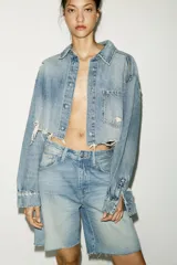 Bermuda de jean celeste de tiro medio con cinco bolsillos. Detalle de trabilla ajustable en espalda. Bajo con terminación desflecada. Cierre frontal con botones metálicos.