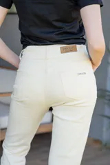Pantalón jean negro de tiro alto, con cinco bolsillos, confeccionado en tela con elastano. Tiene cierre frontal con doble botón y cierre metálico, y detalle de cuero en la parte delantera de la pretina.