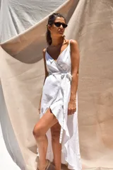 Vestido largo blanco de crepé con escote en V, breteles finos y corte envolvente con volados.