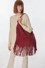 Bolso bandolera de gamuza color beige con flecos largos en la parte inferior.