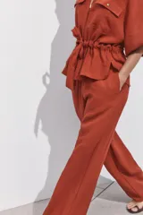 Pantalón marrón de tiro alto con cintura elástica, bolsillos delanteros y pernera ancha.