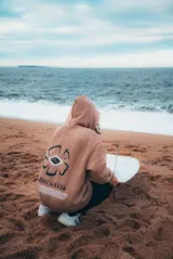 Buzo hoodie marrón con estampado en la espalda de una flor con un ojo en el centro y texto en la parte inferior.