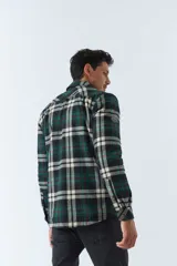 Sobrecamisa de algodón para hombre con interior de corderito, estampado a cuadros en tonos negro, blanco y azul. Tiene cierre de botones, bolsillos tipo cartera y logo en goma. El modelo usa talle M.