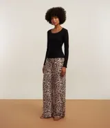 Pijama largo de dos piezas: blusa de canalé negra de manga larga y pantalón de viscosa con estampado de leopardo y lazos en las perneras.