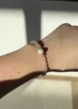 Pulsera elástica con cuentas facetadas de cristal rosa, detalles de acero dorado y una perla barroca de río.