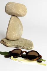 Lentes de sol con montura redonda negra y cristales verdes.