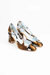 Zapatos de tacón con estampado animal print en tonos marrón, blanco y negro. Tienen punta fina, pulsera con hebilla lateral y tacón ancho. Interior de piel y suela de cuero.