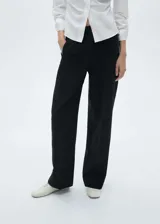 Pantalón de vestir negro de corte recto, con tiro medio, pinzas delanteras, bolsillos laterales y traseros de ribete.