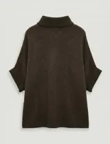 Capa o poncho tejido color verde esmeralda, con cuello polera alto que se cierra con un botón grande en el lateral. Presenta mangas cortas estilo japonesa y un calce amplio.