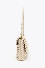 Bolso alargado color beige con diseño trenzado, asa bandolera y tirador con pulsera de mano. Incluye bolsillo interior y cierre con solapa y botón imantado.