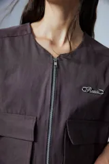Chaleco corto color marrón confeccionado en gabardina con cierre metálico frontal, bolsillos con fuelle y badana de PU en la espalda.