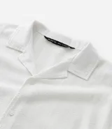 Camisa negra de corte boxy con cuello bowling y abotonadura frontal. Texturizada con diseño jacquard. De manga corta.