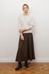 Falda larga de jean azul oscuro, corte acampanado con paneles y costuras visibles.