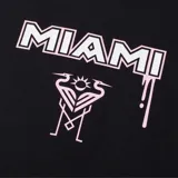 Remera blanca de manga corta con cuello redondo. Estampado frontal con la palabra "Miami" en cursiva sobre el escudo del Inter de Miami.