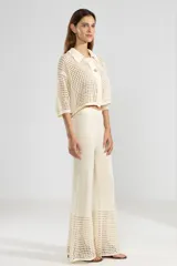 Pantalón largo color crema, tejido en punto calado, con corte Oxford y cintura elástica.