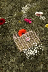 Bolso de mano tejido a crochet en trapillo grueso color borgoña, con asa corta y cierre con botón metálico plateado con logo.