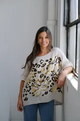Remera beige de corte holgado con estampado de flores abstractas en dorado y negro.
