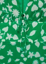 Vestido corto negro con estampado de lunares blancos, escote en V con lazo, mangas cortas y falda con volantes.