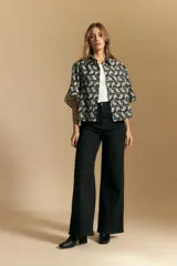 Camisa de manga corta con cuello camisero, confeccionada en tela estampada con diseño paisley en tonos negro, beige y azul.