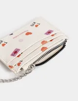 Tarjetero de cuerina color crema con estampado de corazones, flores y textos alusivos a Tokio y Kioto. Tiene cierre superior y mosquetón metálico plateado.