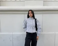 Campera entallada de bengalina color celeste, con cierre frontal, cuello subido, bolsillos delanteros y mangas acampanadas con botones a presión en los puños.