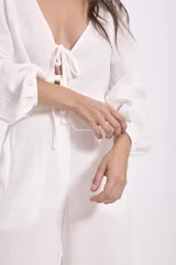 Blusa blanca de manga larga con escote en V y lazos para atar en el frente.