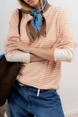 Remera de tejido de punto a rayas horizontales color naranja y blanco, de corte recto, cuello redondo y mangas largas.