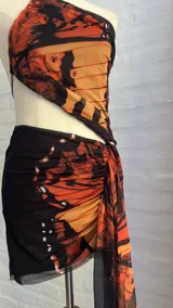 Minivestido con estampado de mariposas en tonos naranja y negro, con escote halter asimétrico y abertura en la cintura.