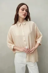 Camisa celeste de calce relajado con cuello clásico, mangas tres cuartos amplias y botones nacarados.