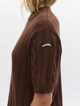 Remera de punto negra con cuello redondo y mangas cortas. Presenta un diseño de tejido con trenzas verticales.