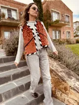 Chaleco color crema con ribete amarillo, de corte recto y sin mangas.