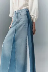Falda larga acampanada de denim rígido con diseño patchwork en distintos tonos de azul y ruedo desflecado.