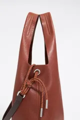 Bolso de mano negro con exterior de piel y estructura blanda. Incluye asa extraíble, bolsillo interior y etiqueta de tejido. Presenta logo metálico BIMBA Y LOLA con acabados metálicos plateados.