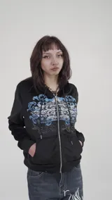 Campera corta negra de terciopelo con cierre frontal y capucha. Presenta un estampado con motivos florales y texto en azul y blanco. Corte ajustado.