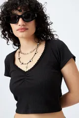 Remera corta negra de punto acanalado con escote en V fruncido y puntilla en el borde.
