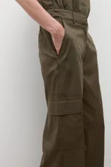 Mono de color verde oliva con cuello camisero, cierre frontal de botones y bolsillos tipo cargo. Presenta mangas cortas y cintura marcada.