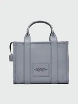 Bolso tote pequeño de cuero color negro, con doble asa corta y correa lateral. Estampado frontal con el nombre de la marca y el tipo de bolso.