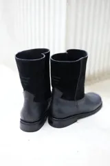 Botas de cuero vacuno color negro, con caña media y suela de caucho.