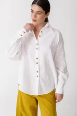 Camisa blanca de lino con botones de madera, corte recto y mangas largas.