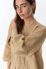 Camisa celeste de lino con botones, mangas largas abullonadas y detalles de crochet en el frente y los puños.