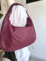 Cartera hobo color borgoña, confeccionada en cuero trenzado.