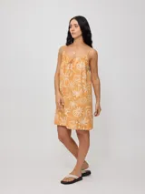 Vestido corto negro con estampado de palmeras, soles y estrellas en color crema. Diseño suelto con breteles finos y escote recto con lazo ajustable.