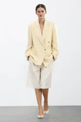 Zapato de tacón en piel color beige con abertura lateral, punta fina y cierre con tira ajustable. Tacón alto fino de 10,5 cm.