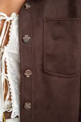 Sobrecamisa color verde militar, de corte oversize, con cuello camisero, cierre frontal con botones y bolsillos de parche en el pecho. Confeccionada en gamuza de cuero vegano.