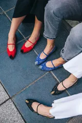 Bailarinas de piel bicolor, con pulsera y múltiples calados. La parte delantera lleva una rejilla transparente roja. La punta y el talón son de terciopelo de seda negro con lunares rojos.